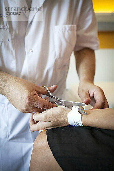 Krankenschwester schneidet das Identifikationsarmband ab  bevor der Patient entlassen wird.
