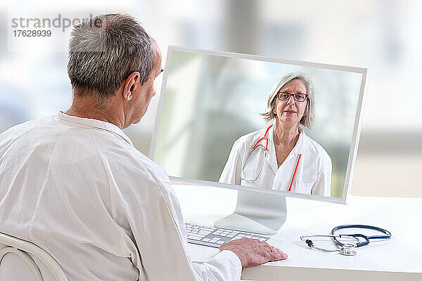 Krankenhausarzt mit Laptop  der einen Online-Anruf mit einem Spezialisten führt.