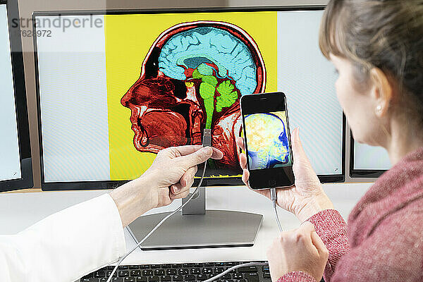 Forscher erklärt einer Frau  wie man bald sein Handy direkt ans Gehirn anschließen kann.