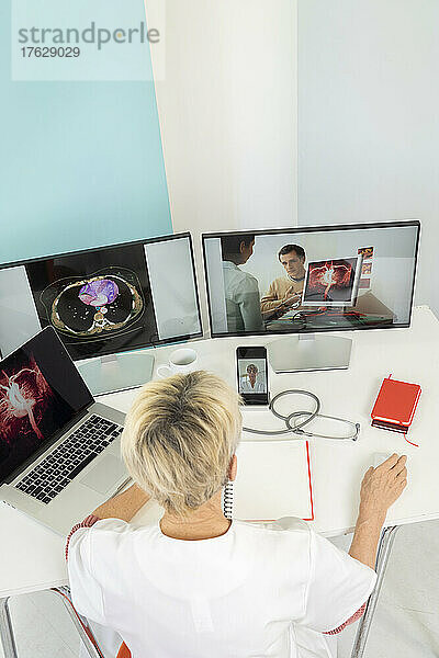 Telekonsultation zwischen zwei Ärzten mit medizinischen Bildern von Mägen auf einem der Bildschirme.