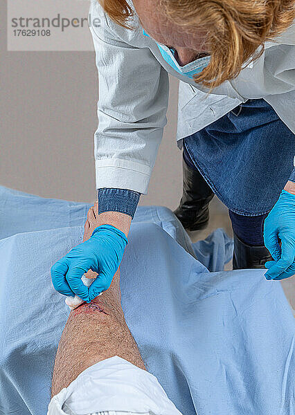 Frisch blutige Verletzungswunde am Schienbein des Beins. Klebestiche  um den Schnitt zu halten.