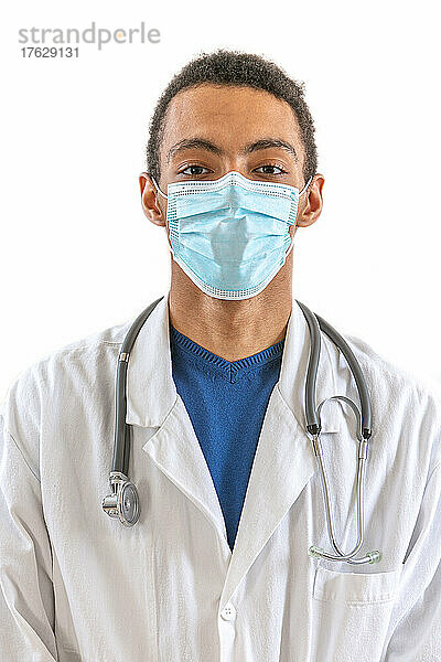 Frontalporträt eines jungen Arztes  der eine Maske trägt  isoliert auf weißem Hintergrund.