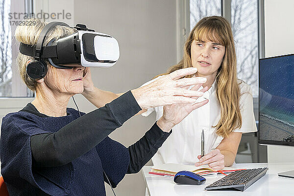 Ältere Frau während einer Therapiesitzung mit einem Virtual-Reality-Headset unter Aufsicht eines Therapeuten.