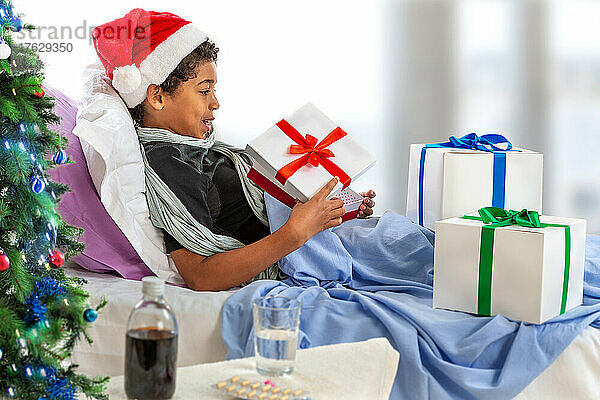 Kleiner Junge mit Weihnachtsmütze erhält ihr Geschenk  während sie im Krankenhaus ist