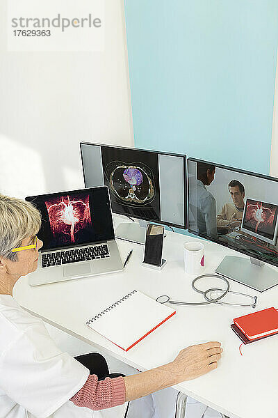 Telekonsultation zwischen zwei Ärzten mit medizinischen Bildern von Mägen auf einem der Bildschirme.