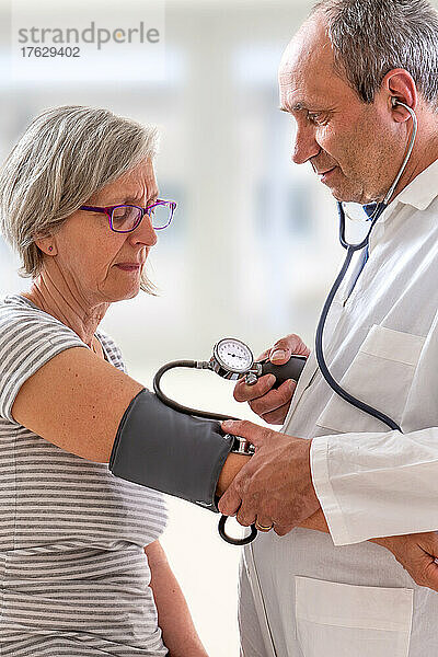 Arzt misst einem Senior den Blutdruck.