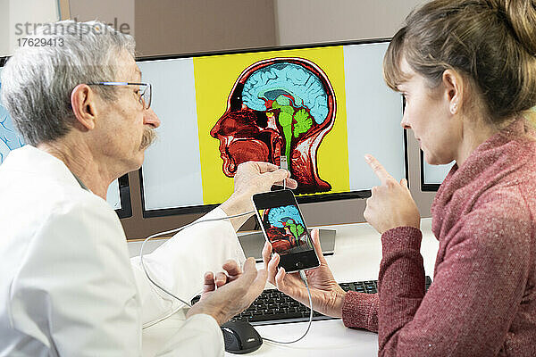 Forscher erklärt einer Frau  wie man bald sein Handy direkt ans Gehirn anschließen kann.
