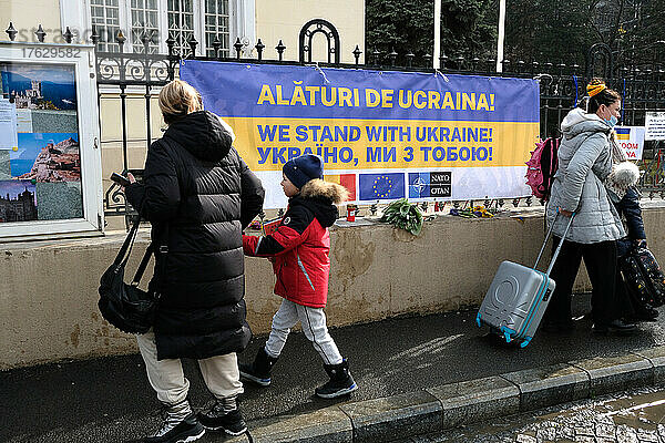 Ukrainische Flüchtlinge vor der Botschaft der Ukraine – Bukarest – Rumänien  um einen biometrischen Reisepass zu erhalten. An den Toren der Botschaft sind Blumen und Banner zu Ehren der im Krieg gefallenen Ukrainer angebracht