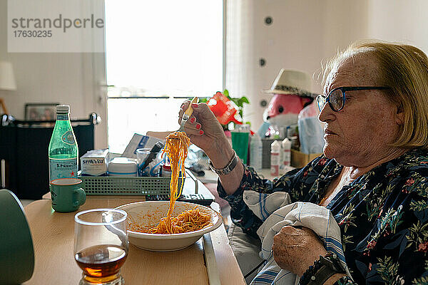 Betreuerin in einem Altersheim  die sich um eine Siebzigjährige mit Parkinson kümmert  damit diese kochen und putzen kann.
