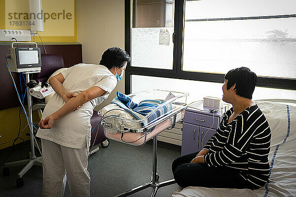 Mutter und Hebamme kümmern sich in einem Krankenhauszentrum um das Neugeborene.