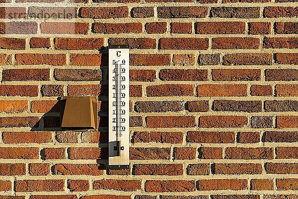 Thermometer an einer roten Backsteinmauer