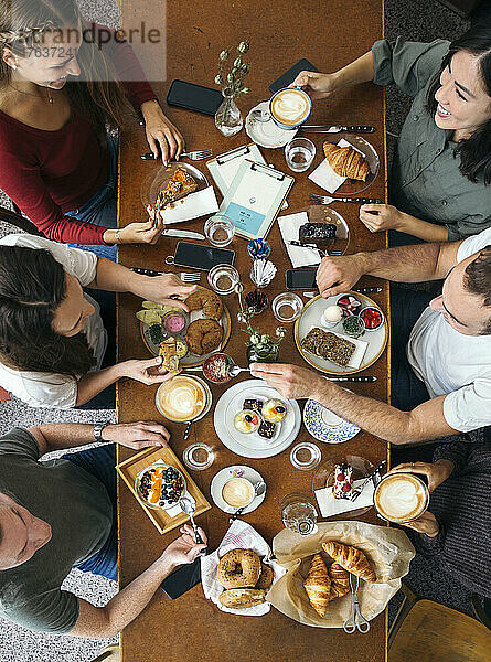 Blick von oben auf eine Gruppe von Freunden  die ihr Frühstück am Tisch im Restaurant genießen