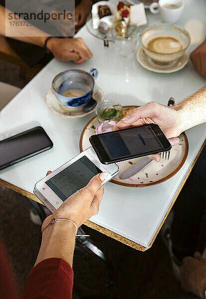 Nahaufnahme eines Mannes  der im Restaurant mit seinem Smartphone bezahlt
