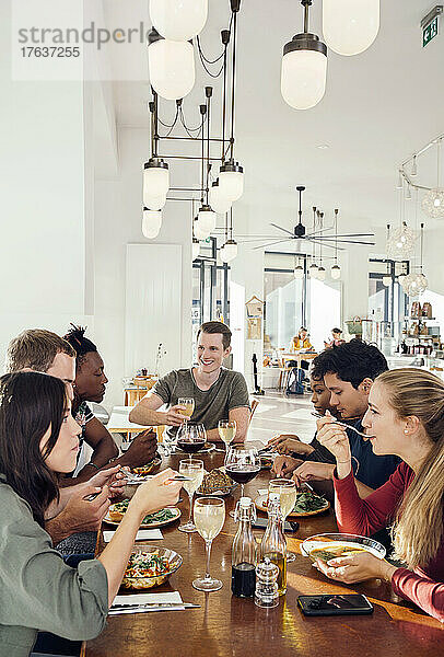 Eine Gruppe lächelnder Freunde genießt das Essen im Restaurant