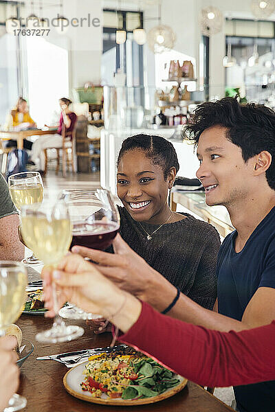Lächelnde Freunde stoßen im Restaurant mit Wein an
