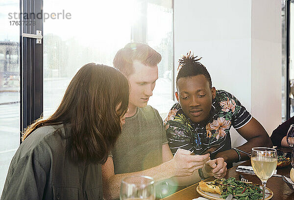 Freunde schauen im Restaurant auf ihr Smartphone
