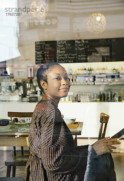 Lächelnde Frau mit digitalem Tablet im Café