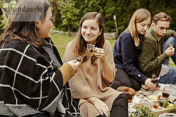 Lächelnde Freunde genießen Picknick im Garten