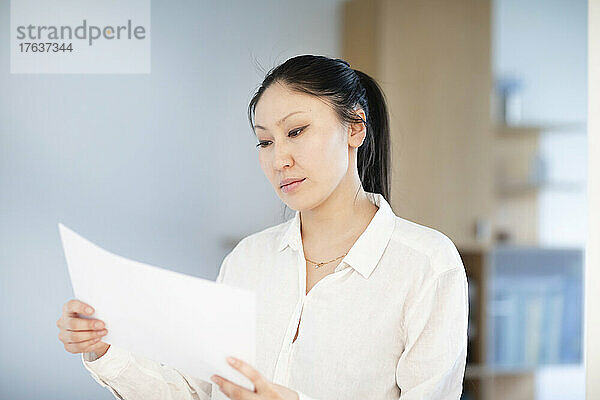 Seriöse Geschäftsfrau schaut sich Dokumente im Büro an