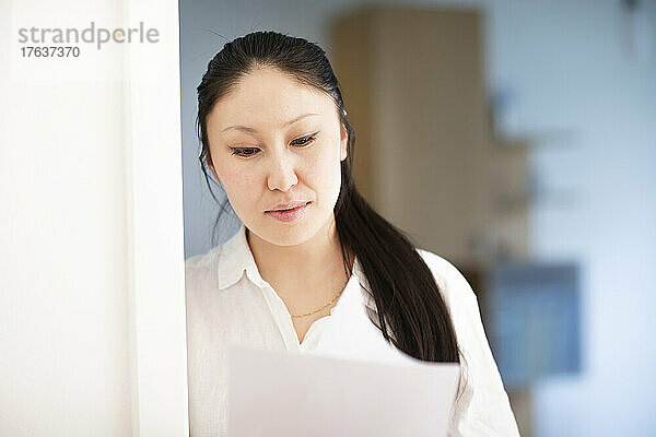 Seriöse Geschäftsfrau schaut sich Dokumente im Büro an