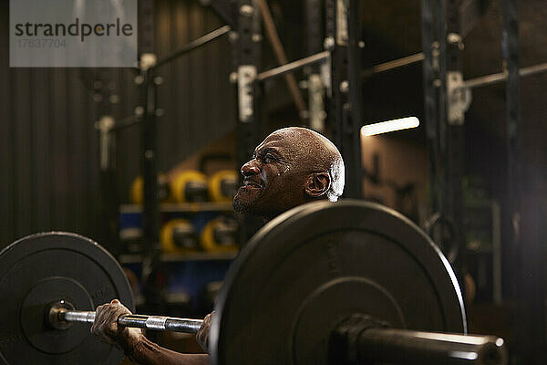 Mann mit Schweiß im Gesicht beim Gewichtheben im Fitnessstudio