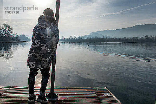 Italien  Rückansicht eines Jungen  am Pier am ruhigen See