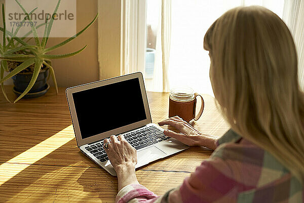 Frau benutzt Laptop zu Hause