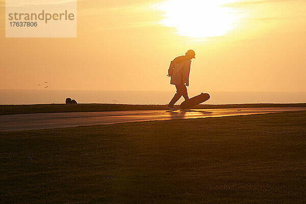 Reifer Mann beim Skateboarden bei Sonnenuntergang