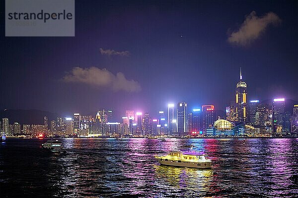 Hongkong Skyline Stadtbild Wolkenkratzer in der Innenstadt über Victoria Harbour in den Abend mit Touristen Boot Fähren beleuchtet  Hongkong  China  Asien