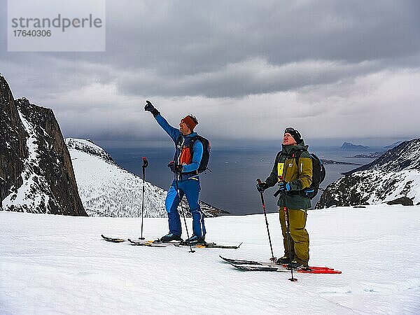 Bergführer deutet seinem Gast den weiteren Weg  Skitour auf der Insel Senja  Troms  Norwegen  Europa
