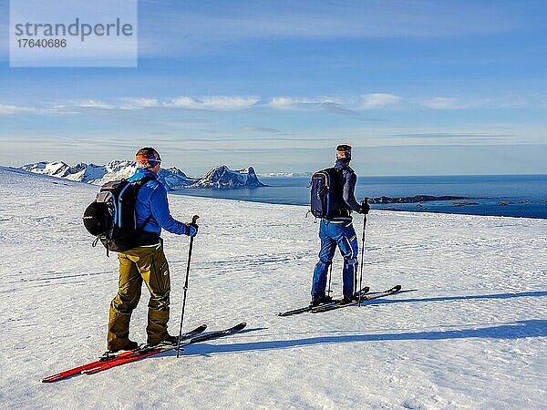 Zwei Skibergsteiger mit Blick aufs Meer  hinten der Teisten  Bergsjforden  Insel Senja  Troms  Norwegen  Europa