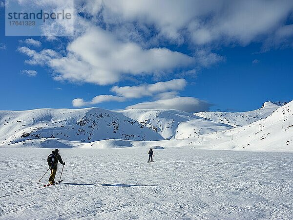 Zwei Skitourengeher überqueren einen gefrorenen See im winterlichen Gebirge  Insel Senja  Troms  Norwegen  Europa