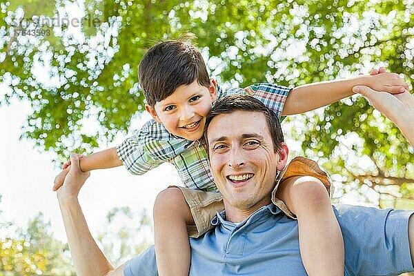 mixed-race father and son playing piggyback together in the park