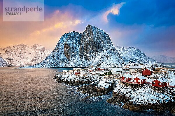 Famous tourist attraction Hamnoy fishing village on Lofoten Islands  Norway with red rorbu houses. With falling snow in winter on sunrise
