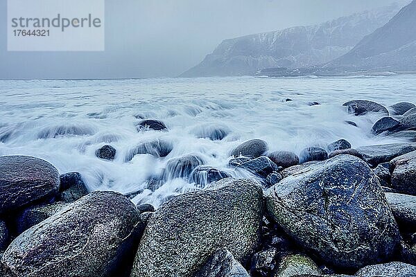 Waves of Norwegian sea surging on stone rocks at Unstad beach  Lofoten islands  Norway in winter storm. Long exposure