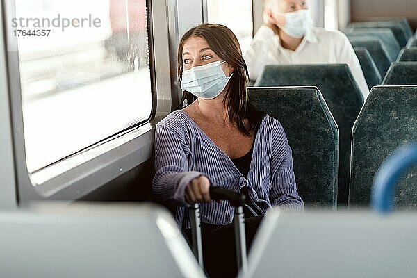 Serious passengers in protective masks during their train day trip