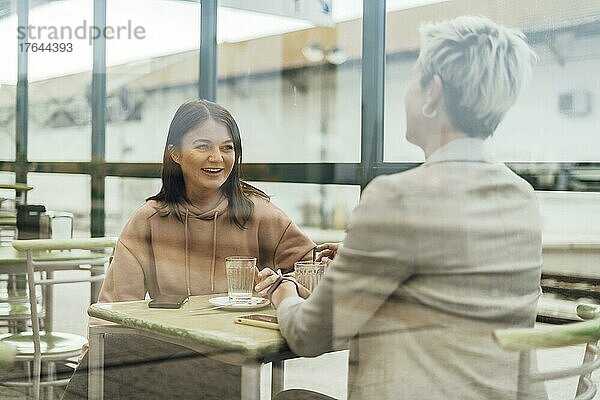 Two female friends drinking coffee and enjoying time in the cafe at railway station