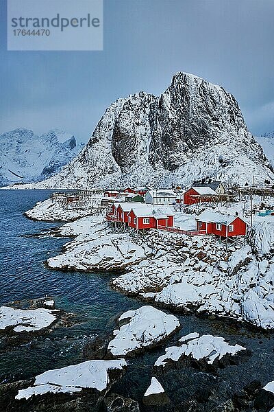 Iconic Hamnoy fishing village on Lofoten Islands  Norway with red rorbu houses. With falling snow in winter