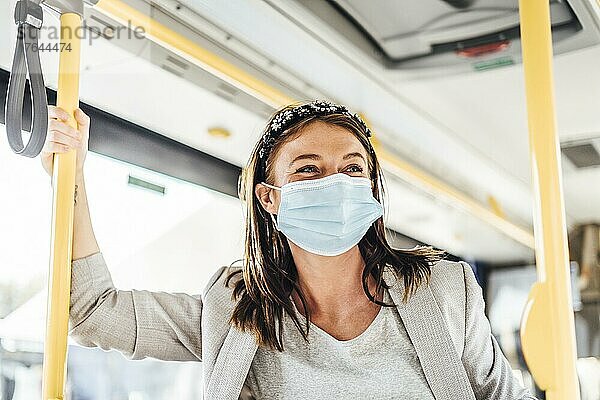 A young woman wearing protective mask commuting by the public bus
