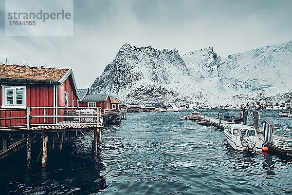 Traditional red rorbu houses in Reine fishing village in winter and pier with boats. Lofoten islands  Norway