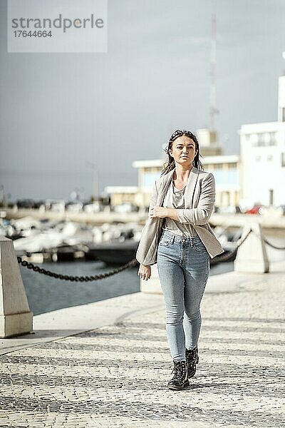 A portrait of a young confident woman walking in the city by marina