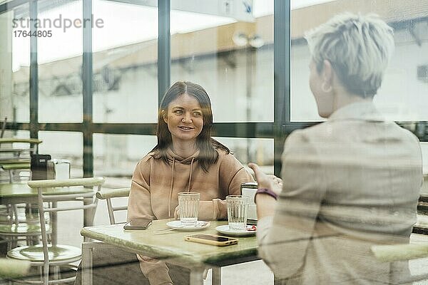 Two female friends drinking coffee and enjoying time in the cafe at railway station