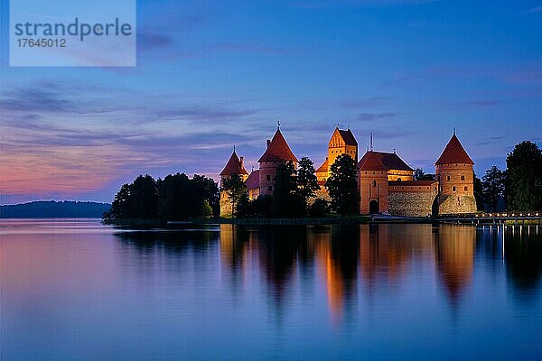 Trakai Island Castle in lake Galve illuminated in twilight reflecting in peaceful water  Lithuania