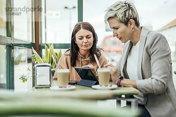 Two female friends drinking coffee and enjoying time in the cafe at railway station