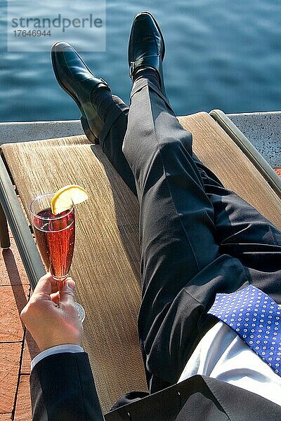 Executive relaxing by the pool with a drink in his hand