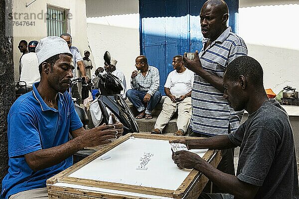 Dominospiel  Männer spielen an Tisch auf dem Platz Jaws Corner in der Altstadt von Stone Town  Unguja  Sansibar  Tansania  Afrika