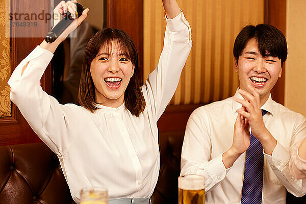 Japanische Geschäftsleute trinken Getränke beim Karaoke