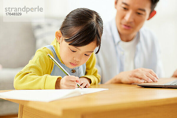 Japanisches Kind lernt zu Hause mit seinen Eltern