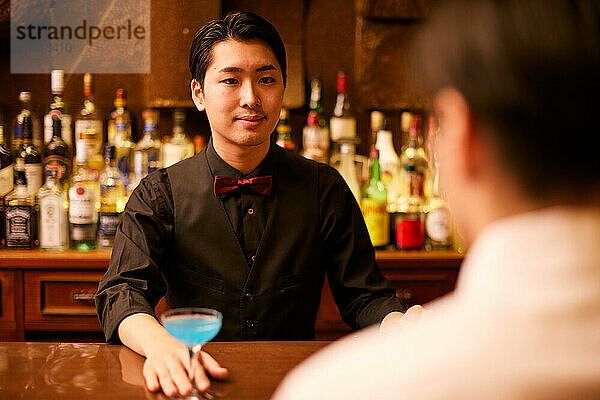 Japanese bartender serving a drink
