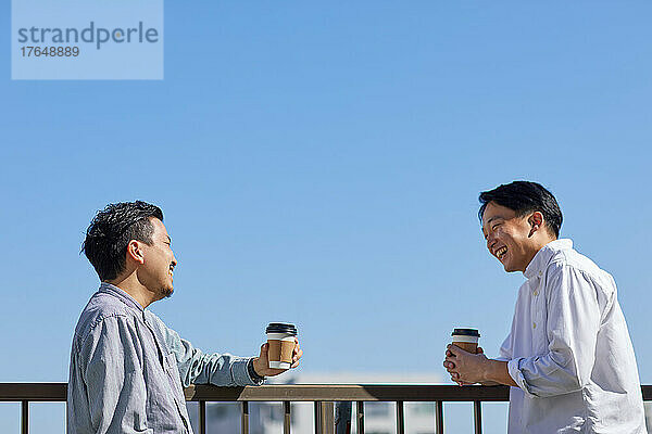 Japanische Männer trinken draußen gemeinsam Kaffee